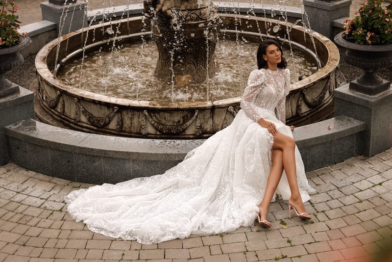 Robe de mariée dentelle brodée, dos nu, manches longues et silhouette princesse — Seraphina par Olya Mak, vue 4, showroom MADAMOON Paris 10e