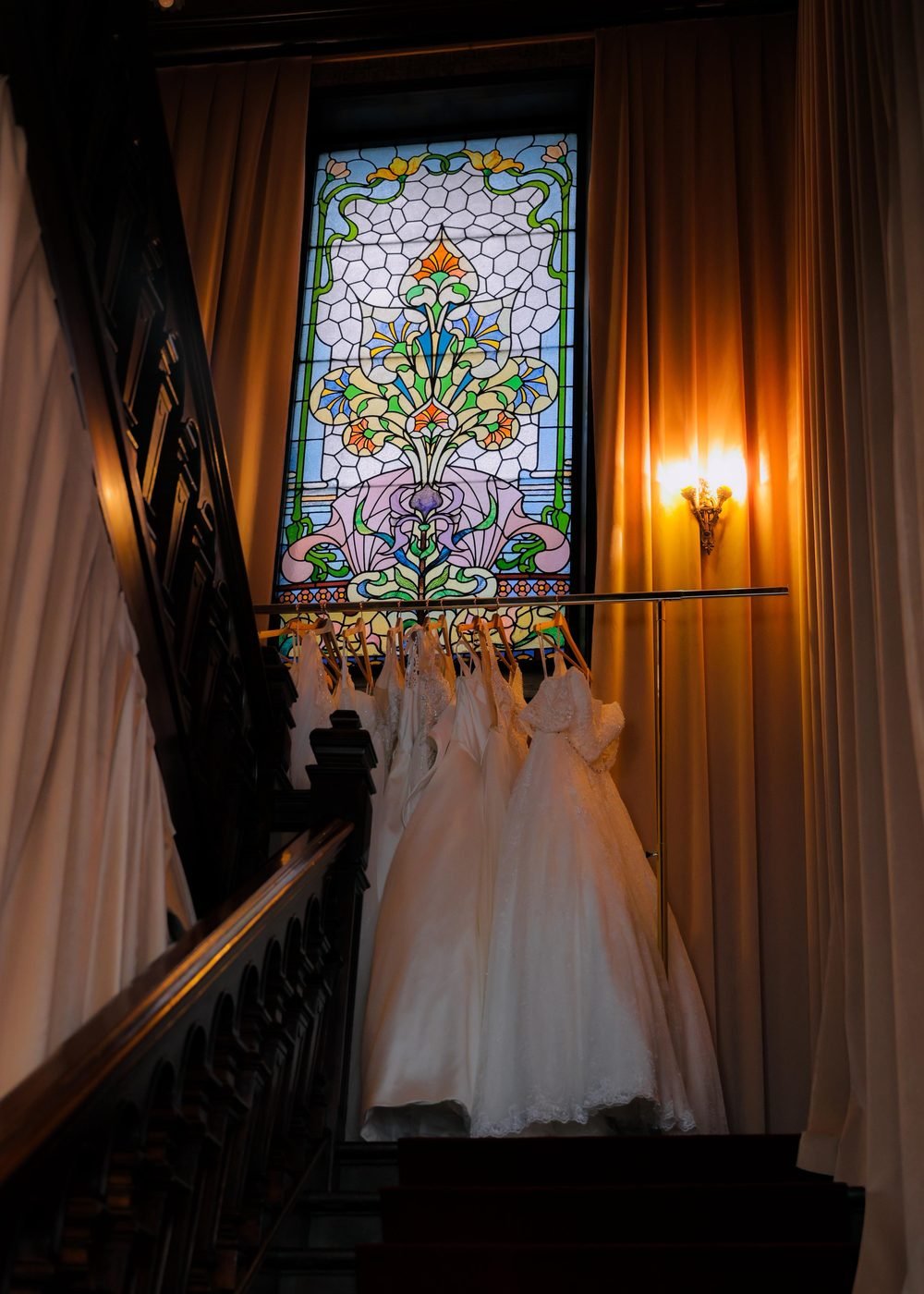 Le vitrail Art nouveau en haut de l'escalier du showroom, et des robes de mariée suspendues à la rampe